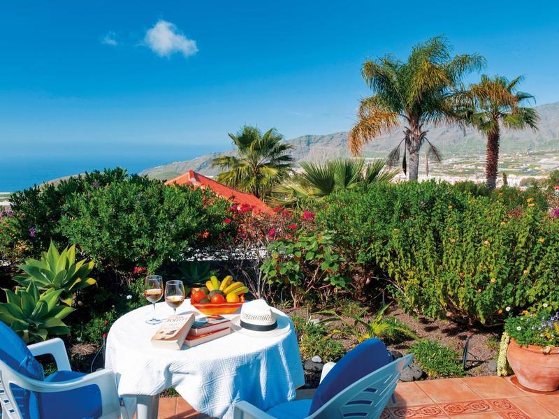 Terrace with set table, blue chairs, and sea view under blue sky