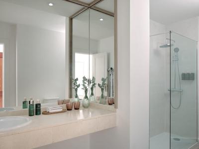 Lichte badkamer met grote spiegel, moderne douche en witte muren.