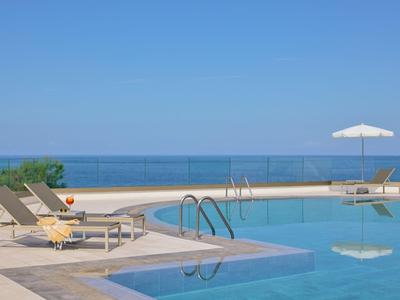 Area piscina moderna con lettini e ombrellone su una terrazza con vista sul mare