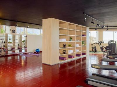 Moderner Fitnessraum mit Hanteln, Laufbändern und großen Fenstern für Tageslicht.