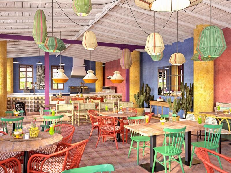 Kleurrijk hotelcafé met talrijke tafels, stoelen en moderne hanglampen.