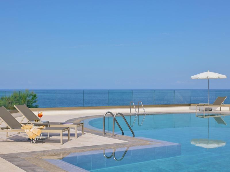 Area piscina moderna con lettini e ombrellone su una terrazza con vista sul mare