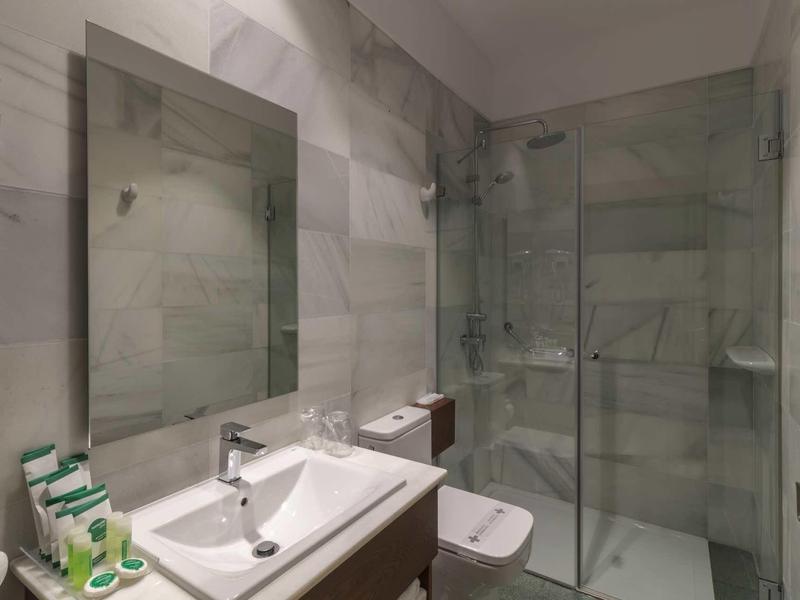 Modernes Badezimmer mit großem Spiegel, weißem Waschbecken und Glasduschkabine.