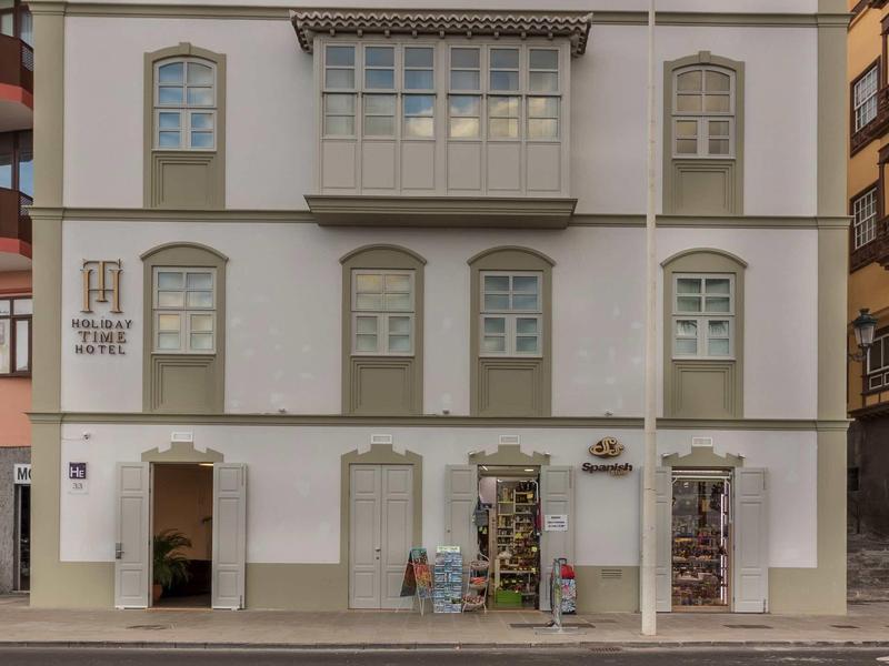 Drei Stockwerke hohes weißes Gebäude mit vielen Fenstern und zwei Eingangstüren an der Straßenseite.