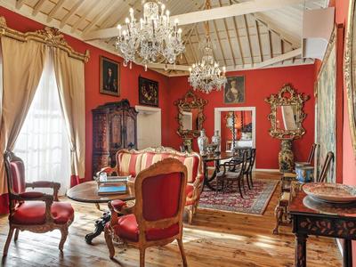 Elegant living room with red walls, antique furniture, and chandeliers in a historic hotel.