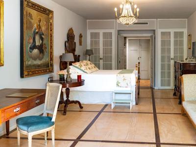 Elegant bedroom with double bed, antique furniture, and large paintings on the walls.