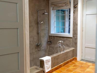 Bathroom with open shower, gray wall tiles, window, and wooden door.