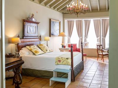 Cozy bedroom with a canopy bed, wooden furniture, and terracotta floor.