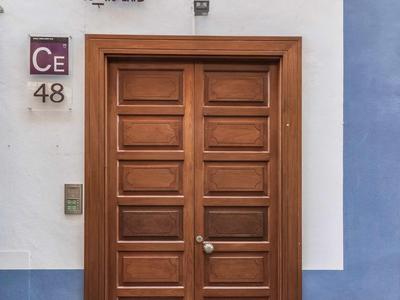 Holztür mit Rechteckpaneelen in weiß-blauem Mauerwerk und Hausnummer 48