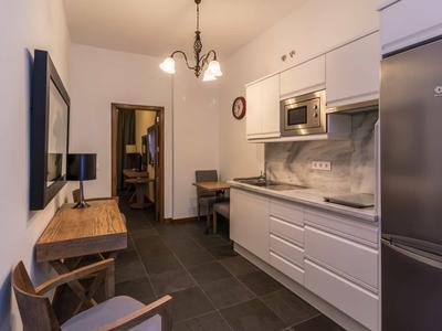 Moderne kleine Küche mit weißen Schränken, grauer Arbeitsplatte und dunklem Fliesenboden.