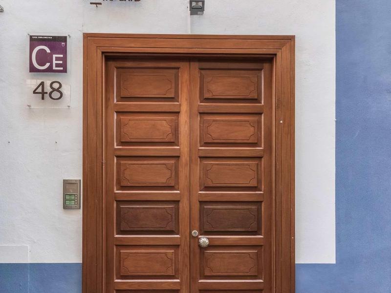 Holztür mit rechteckigen Paneelen, umgeben von weißem und blauem Wandbereich, daneben Hausnummer 48.