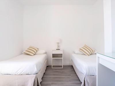 Ein schlicht eingerichtetes Zimmer mit zwei Einzelbetten, Nachttisch und hellem Boden.