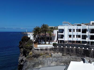 Hotelanlage auf einer Klippe mit Blick auf das blaue Meer unter klarem Himmel.