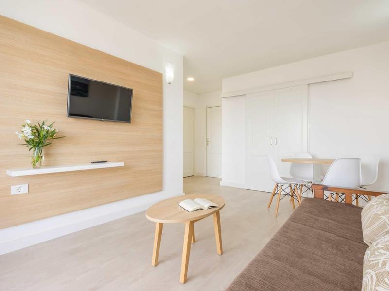 Modern living room with wooden accent wall, wall-mounted TV, and seating area.