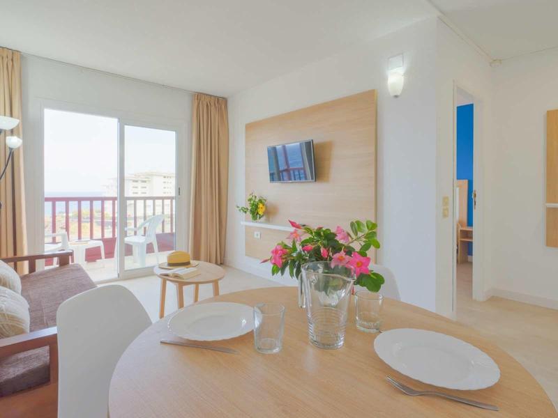 Bright living room with modern furniture, balcony access, and floral decoration.
