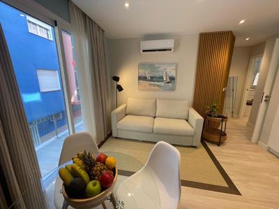 Modern eingerichtetes Hotelzimmer mit Sofa, Esstisch und Obstschale.