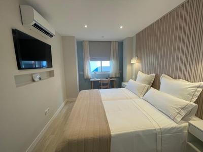 Modernes Hotelzimmer mit Doppelbett, Fernseher und Fenster mit Ausblick.