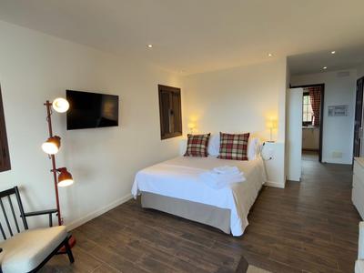 Nowoczesny pokój hotelowy z łóżkiem dwuosobowym, drewnianą podłogą i minimalistycznym wystrojem.