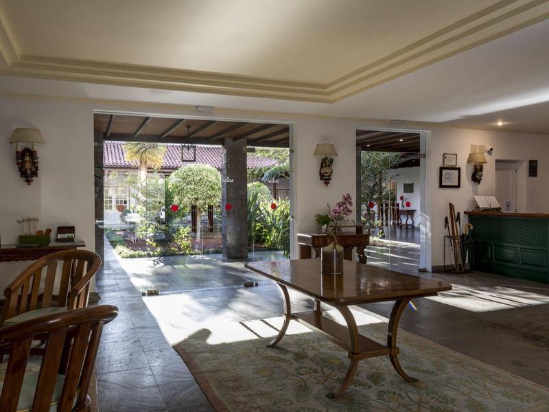 Hol hotelowy z szerokim wejściem na zielony ogród.