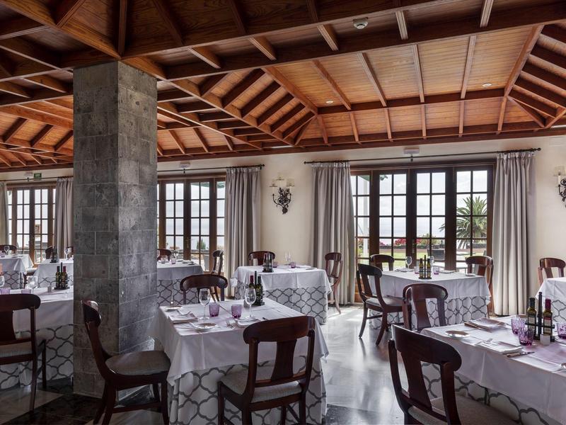 Elegancka sala restauracyjna z nakrytymi stołami i dużymi oknami wpuszczającymi światło.