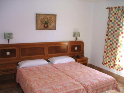 Hotel room with two single beds, nightstands, patterned curtains, and wall decoration.