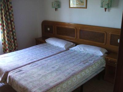 Een eenvoudige hotelkamer met twee eenpersoonsbedden en een houten hoofdeinde.