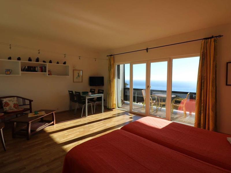 Camera d'hotel luminosa con letto matrimoniale e vista mare da grandi finestre