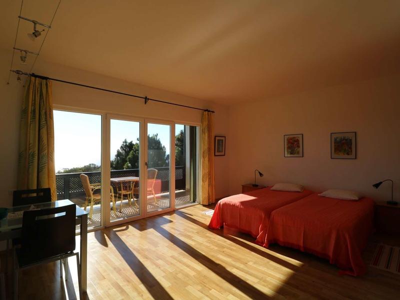 Camera d'hotel luminosa con due letti singoli e ampio balcone con vista.