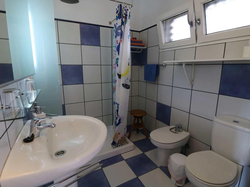 Piccolo bagno con lavabo, WC, bidet e tenda della doccia in una stanza piastrellata blu e bianca.