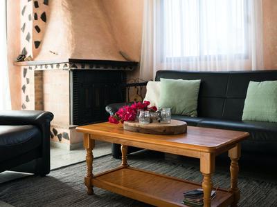 Wohnzimmer mit Holztisch, schwarzen Sofas, hellgrünen Kissen und einem Kamin an der Wand.