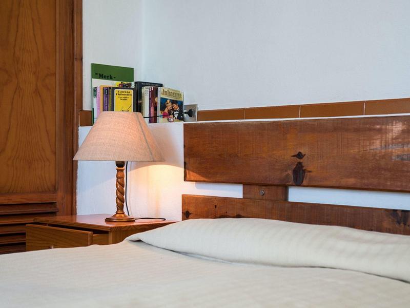 Minimalistický hotelový pokoj s dřevěným nábytkem a postelí s bílým povlečením