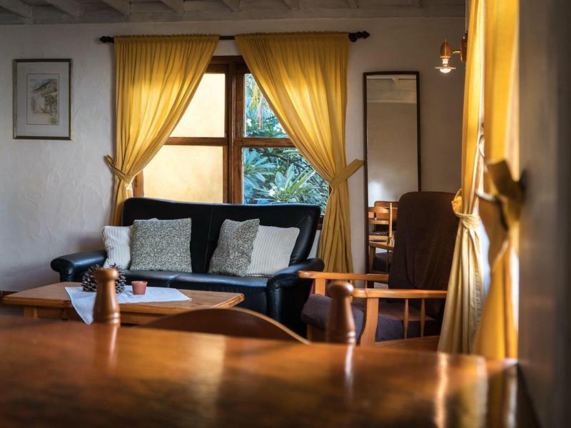 Pohodlný obývací pokoj se žlutými závěsy, pohovkou a dřevěným stolem v hotelovém pokoji.