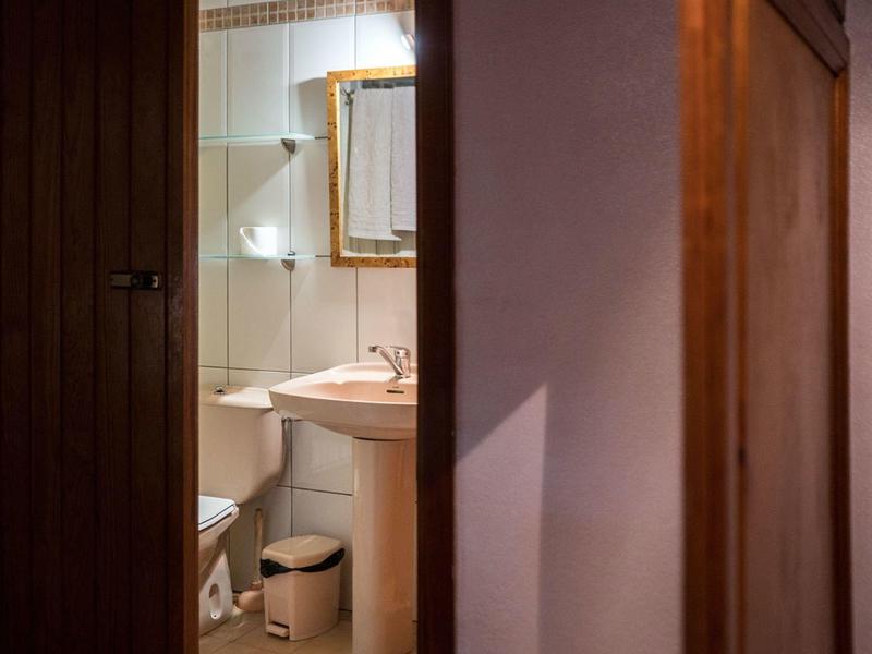 Pohled do malé koupelny se umyvadlem, toaletou a zrcadlem nad umyvadlem.