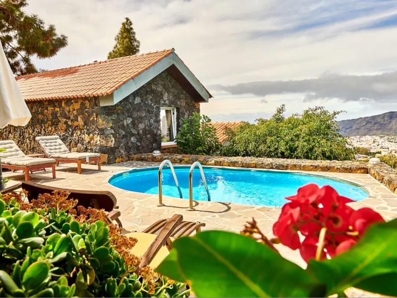 Pohodlný rekreační dům s bazénem na terase, obklopený horami a rostlinami.