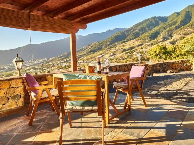 Terasa s dřevěnými židlemi a stolem s výhledem na horskou krajinu na slunečním světle.
