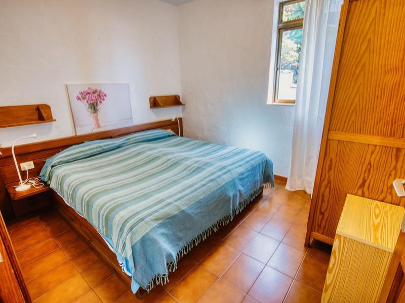 Příjemná ložnice s manželskou postelí, dřevěným nábytkem a oknem s výhledem.