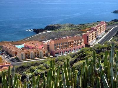 Complejo hotelero en la costa con paisaje árido y cactus en primer plano.