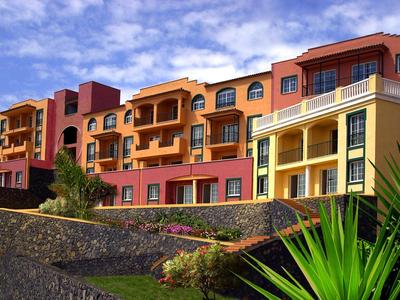 Hotel de varios pisos con fachadas amarillas y rojas bajo cielo nublado.