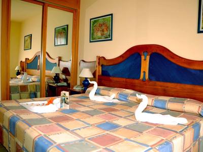 Una habitación de hotel con dos camas, toallas decorativas en forma de cisne y un espejo en la pared.