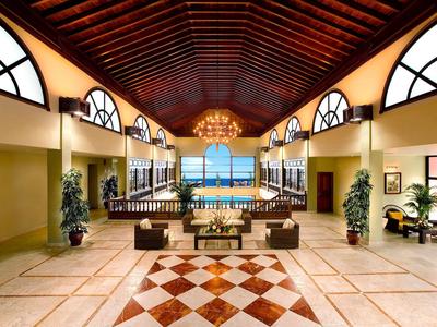 Velká hotelová bazénová oblast s vysokými stropy, dřevěnými trámy a středomořským designem.