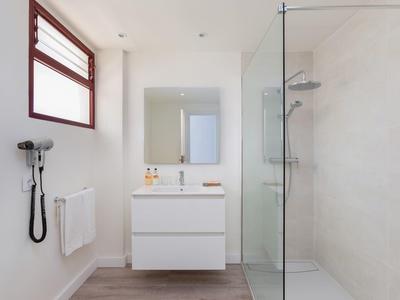 Bright modern bathroom with white sink and glass shower.