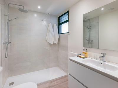 Modern, bright hotel bathroom with large walk-in shower and double sink.