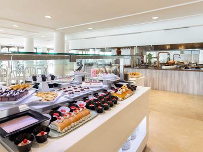 Helles Buffet mit vielfältigem Gebäck, Kuchen und Torten in modernem Raum mit weißem Interieur.