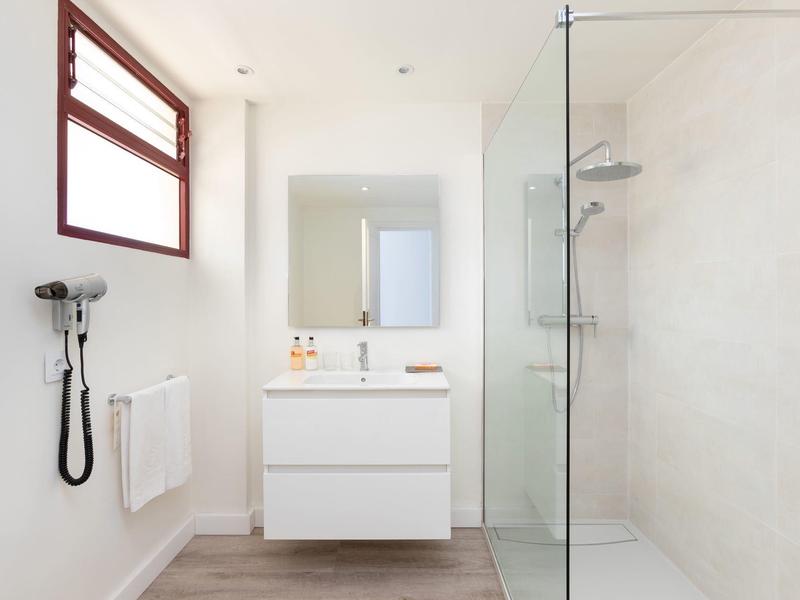 Bright bathroom with glass shower, white vanity, and wooden floor.