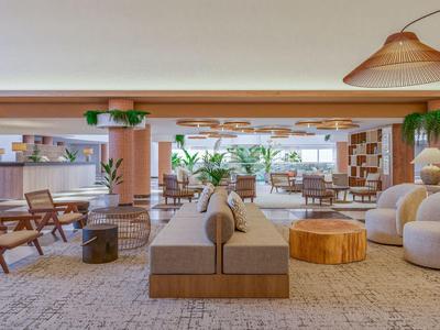 Salon d'hôtel moderne avec sièges confortables, plantes et décoration naturelle.