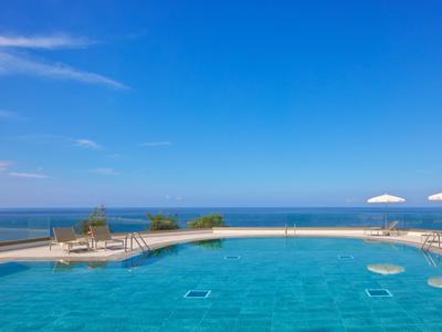 Piscine à débordement avec eau bleue et vue sur la mer sous un ciel clair