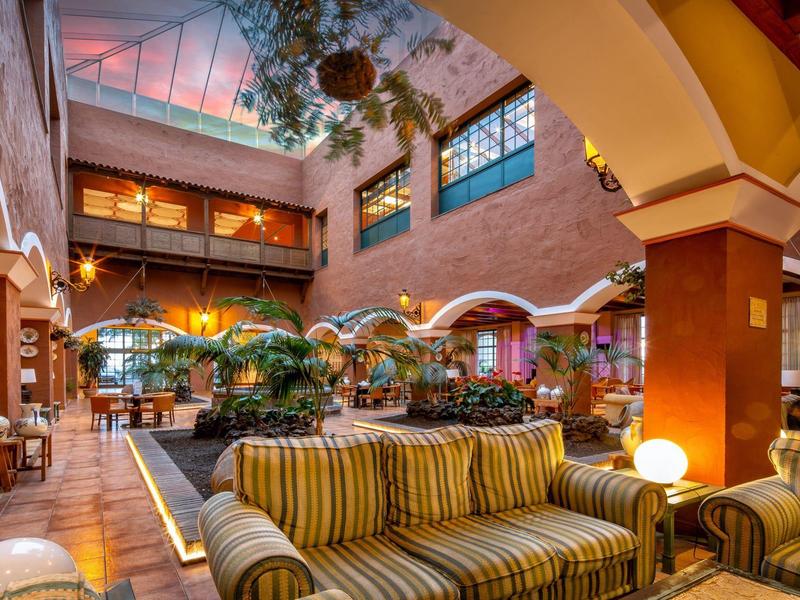 Großer Gastraum mit hohen Decken, Backsteinwänden, gepolsterten Sofas und warmem Licht.