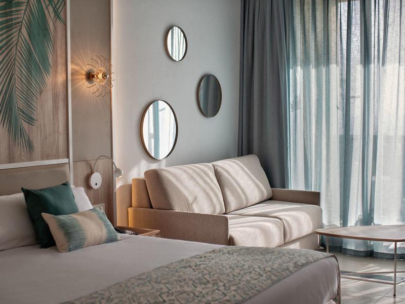 Modern hotelkamer met bed, bank, spiegels en grote ramen