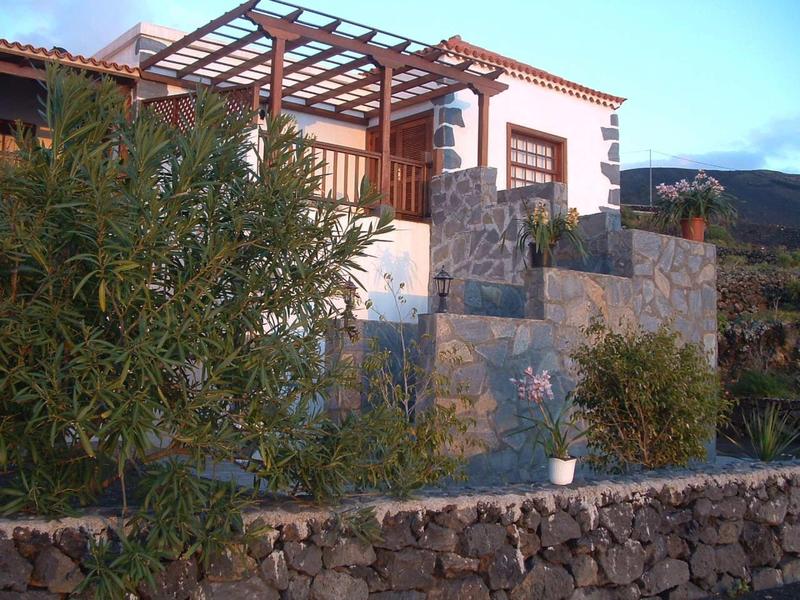Casa con pergola e muro da giardino in pietra naturale in paesaggio soleggiato