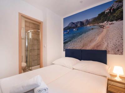 Small bedroom with double bed, nightstand lamp, and large beach photo on the wall.